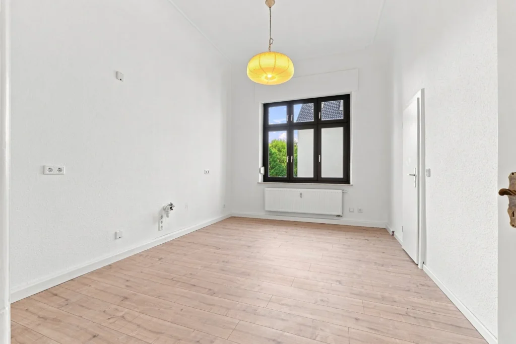 Küchenraum mit Holzboden, großem Fenster und vorhandenen Küchenanschlüssen