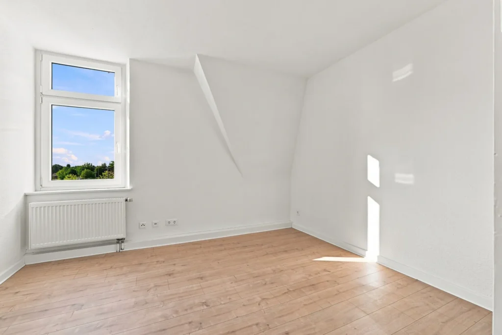 Heller Dachgeschossraum mit Holzboden, großem Fenster und Dachschräge